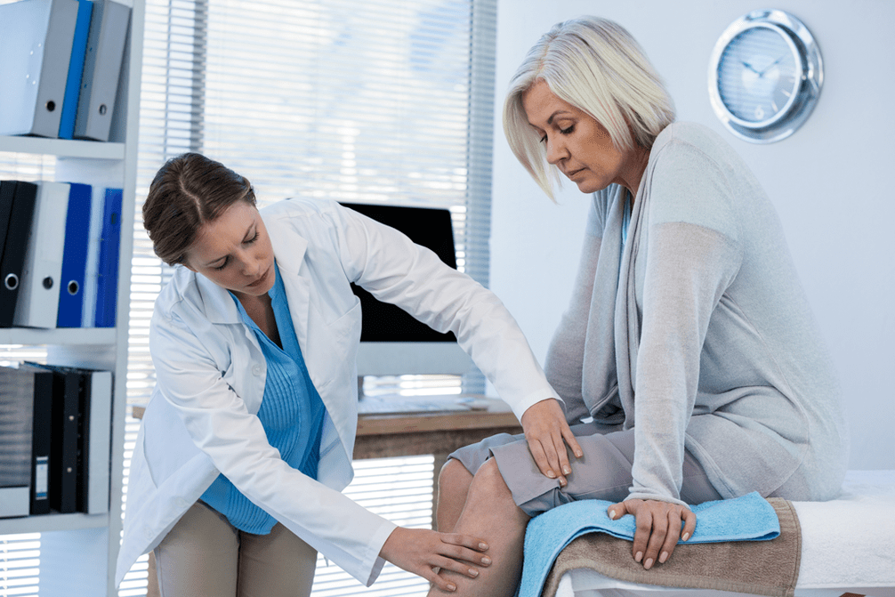 The doctor examines a patient with osteoarthritis of the knee